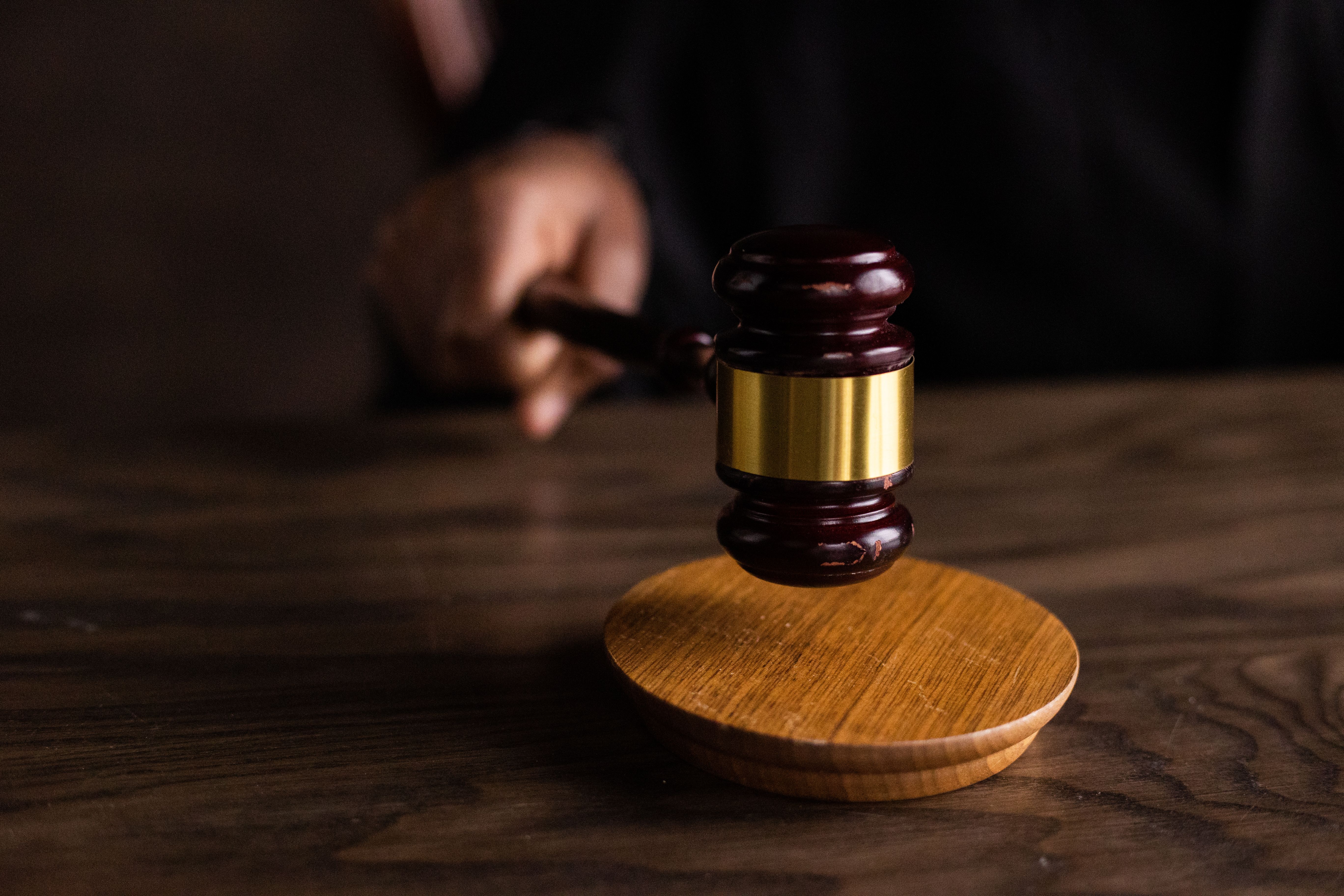 Wooden gavel striking a sound block in a courtroom symbolizing legal authority in litigation
